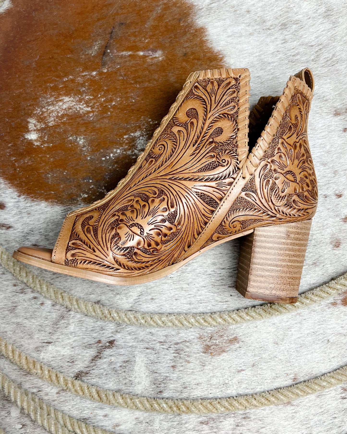 Side view of cowgirl booties with tooled leather, open toe, 2-inch heel, and side slit