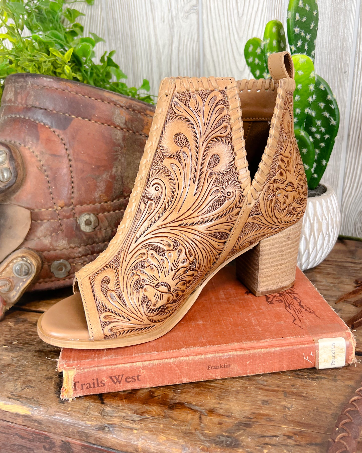 Side view of cowgirl booties with tooled leather, open toe, 2-inch heel, and side slit