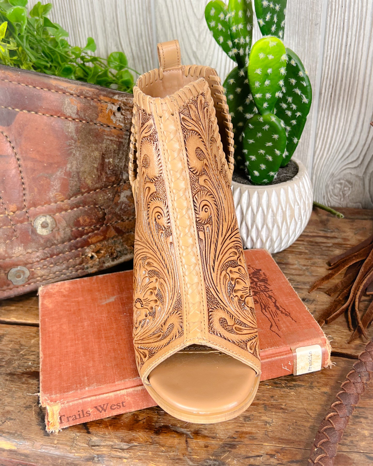 Front view of high heeled western booties with 2-inch stacked heel and floral tooling