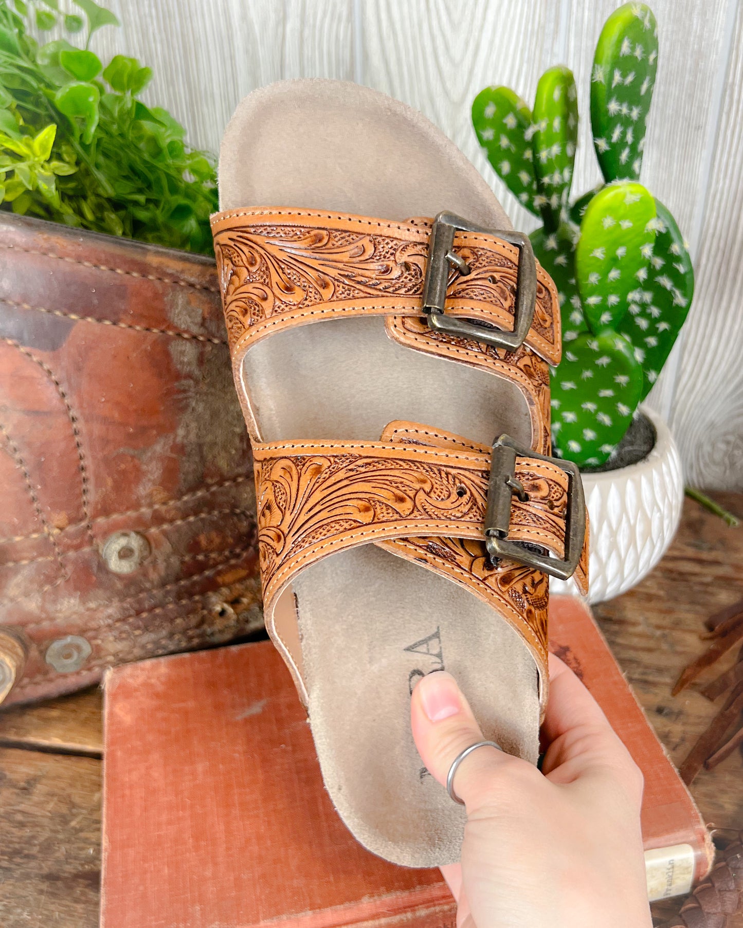 Top-down view of floral tooled leather sandals with double adjustable straps and contoured sole