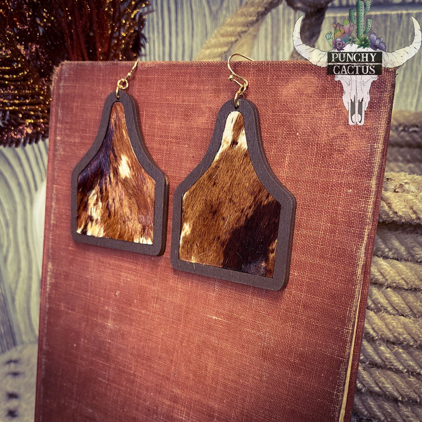western earrings that are cow ear tag shaped with brown and white cow hide center